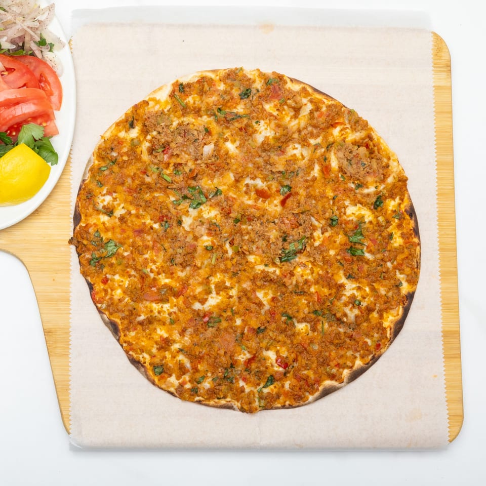 Lahmacun, a Turkish flatbread topped with minced meat and vegetables, served with a side salad.